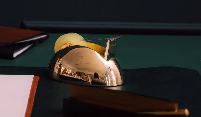 Eleganter goldener Tischabroller auf einem stilvollen Schreibtisch mit Notizbuch und Papier