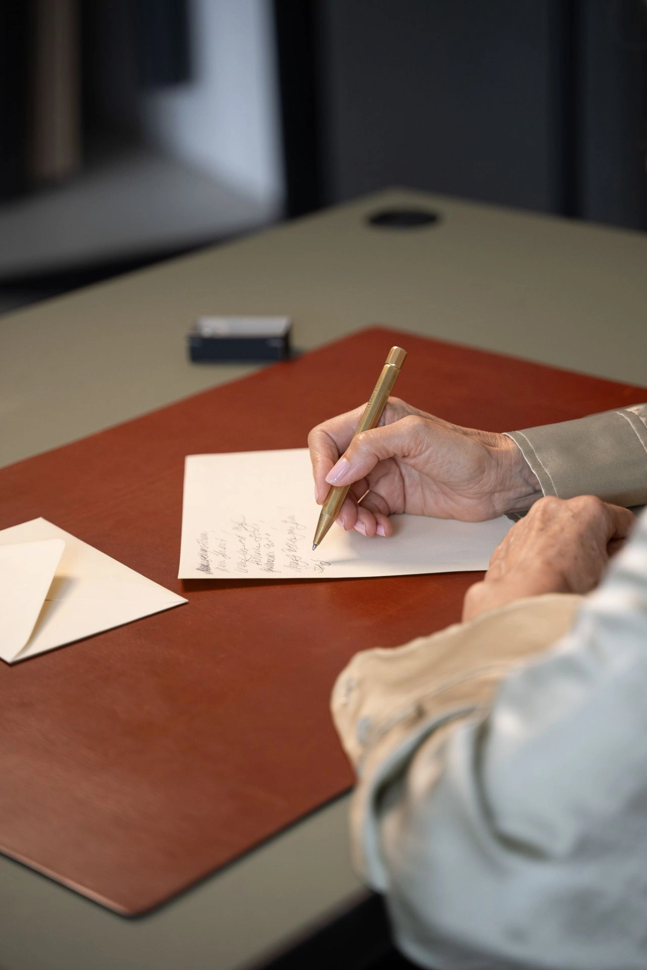 Legendär Kugelschreiber Messing – Handschriftlicher Brief auf Lederunterlage Person schreibt mit einem Legendär Kugelschreiber aus Messing auf Briefpapier – auf Leder-Schreibunterlage